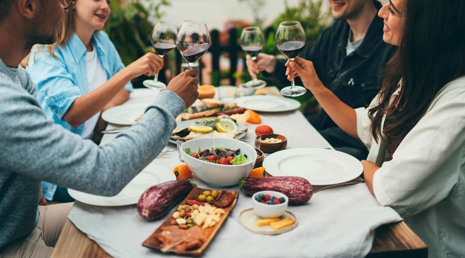 a group of people sitting down to eat holding wine glasses